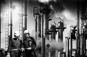 two refinery workers with industrial plant in background